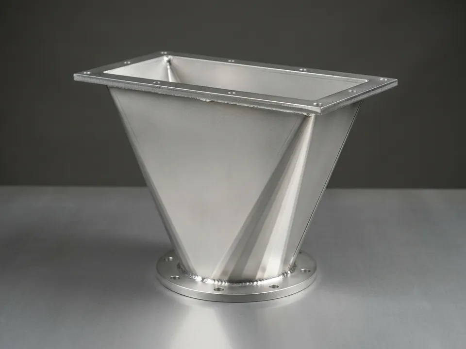 Folded rectangle-to-round transition with flanges at both ends.